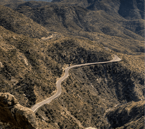 A winding road along a mountainside with steep cliffs to the side
