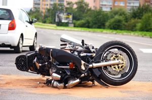 A motorcycle lies on its side in the street after a crash