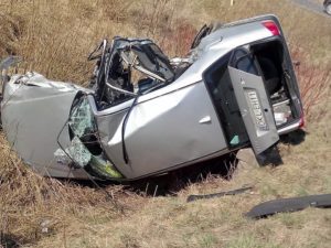 A car lies on its side, mangled, after rolling into a ditch