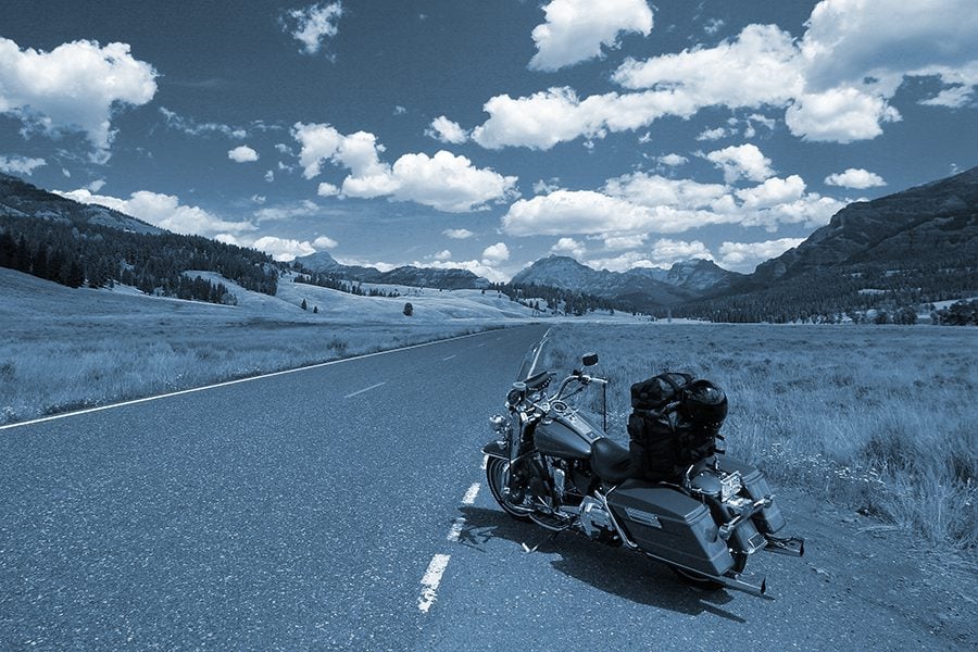  Motorcycle pulled onto the shoulder of a country road on a blue background