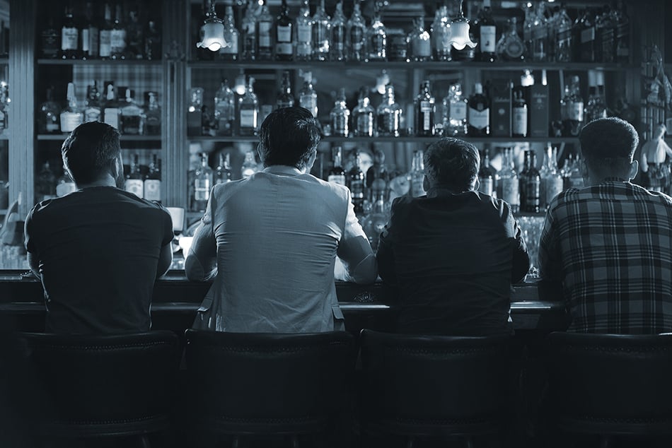  Back view of 4 men sitting at a bar counter