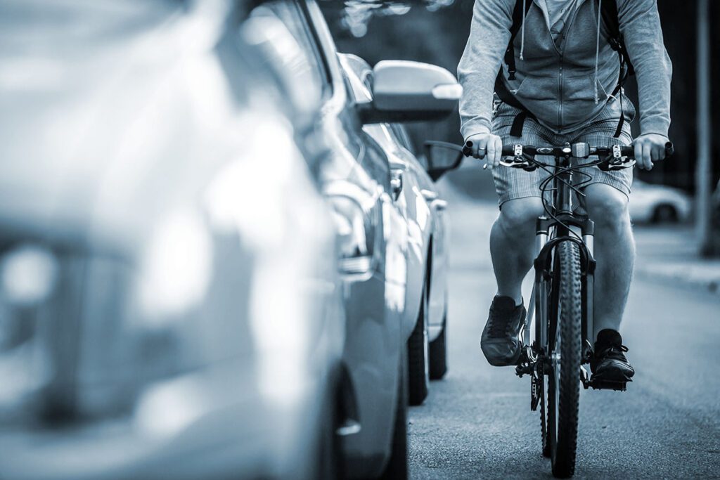  Cyclist rides on the road close to cars in heavy traffic