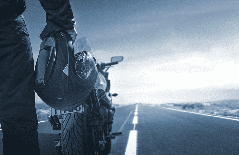 Close up on motorcyclist hold helmet in front of their bike