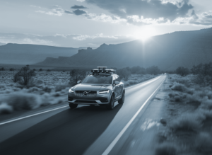 Car drives down a single lane road in the desert