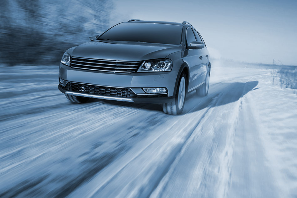 A gray crossover drives on a snowy and icy road in the winter