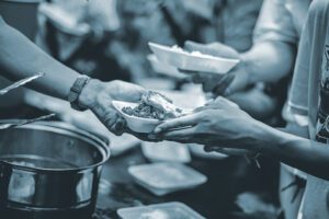 A volunteer hands a plate of food to another person