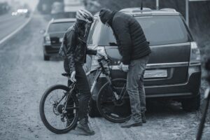 Bicyclist behind and car talking to driver after a collision